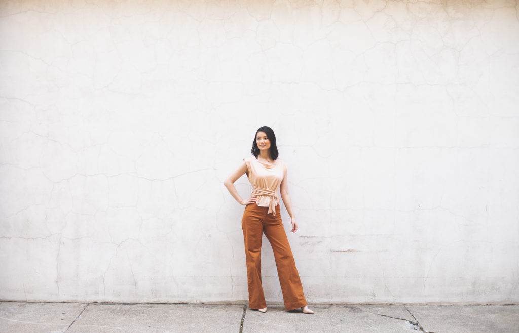 Beautiful images of Kan's Personal Branding Session. A woman is wearing orange pants and standing next to a wall. 