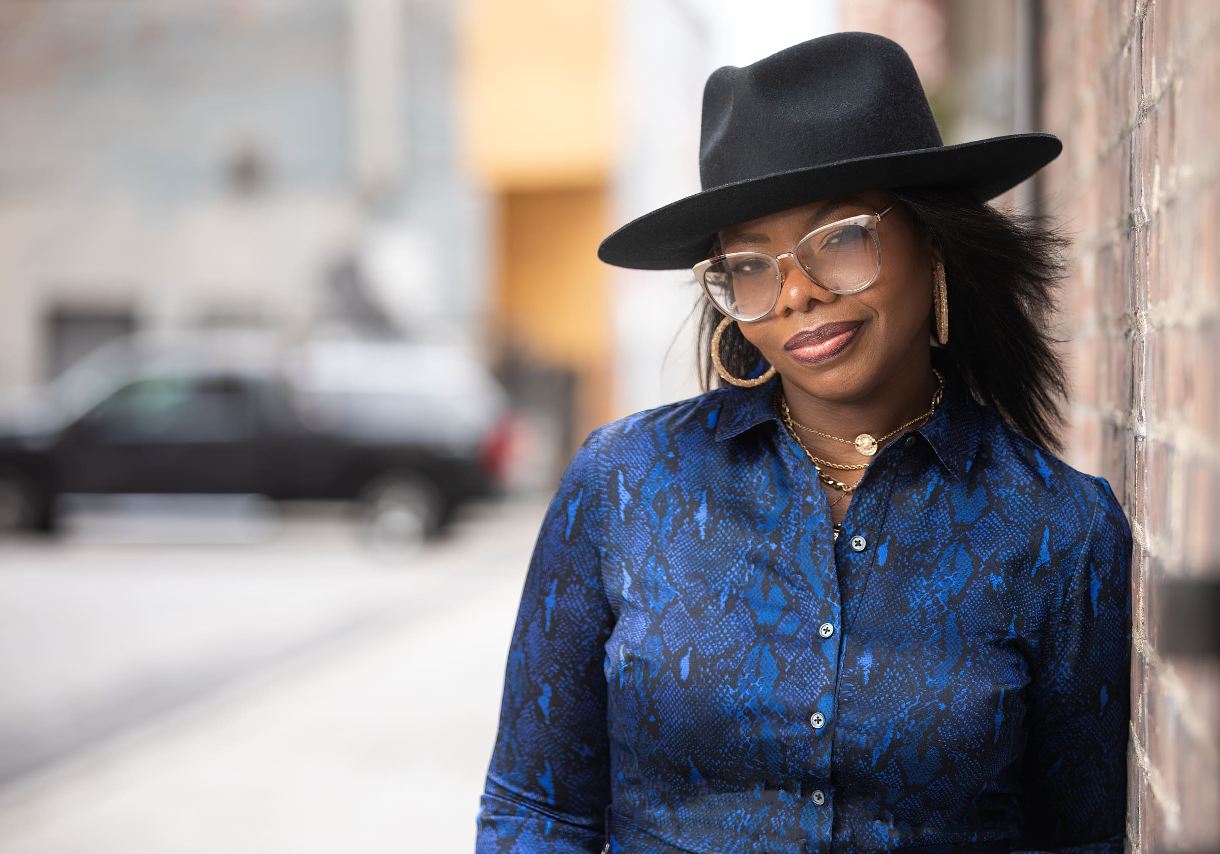Personal branding portrait of Candace Bates in Cincinnati Ohio wearing a black hat and denim top while standing outdoors in an urban setting.