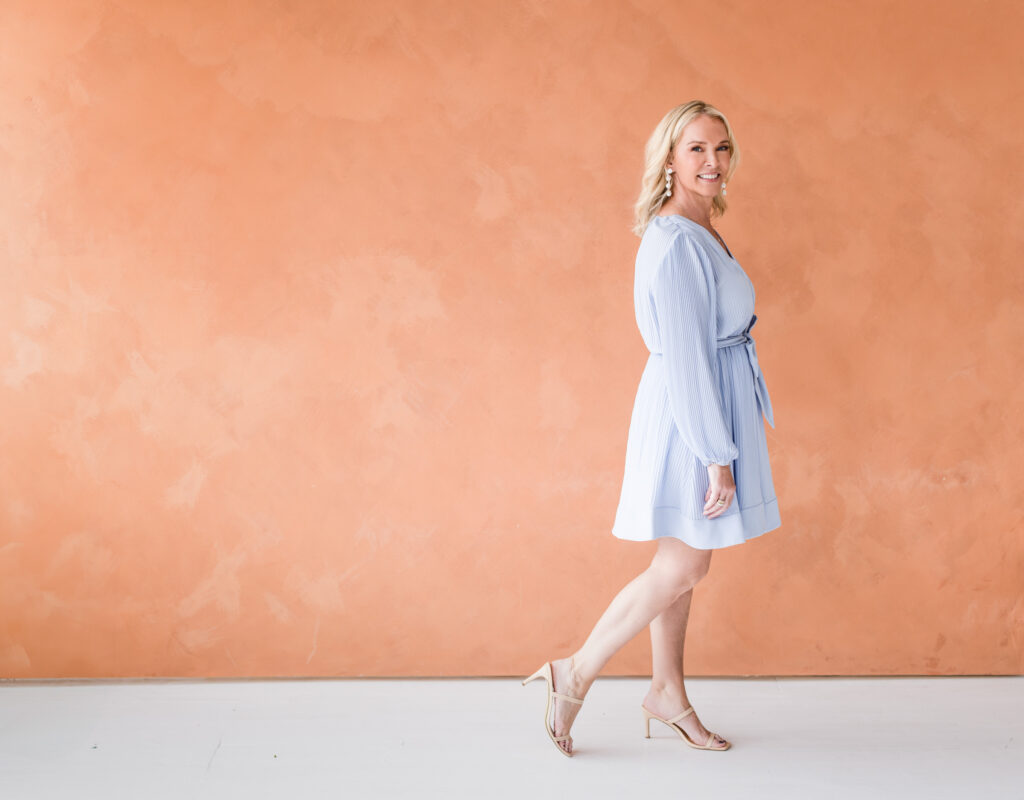 Cathy Major showcases a dynamic and engaging side of her brand in this stylish personal branding portrait. She gracefully walks in front of a textured terracotta backdrop, dressed in a flowing light blue dress. Captured at Janel Lee Photography in Cincinnati, this image radiates warmth, approachability, and effortless sophistication—ideal for connecting with luxury travel clients.