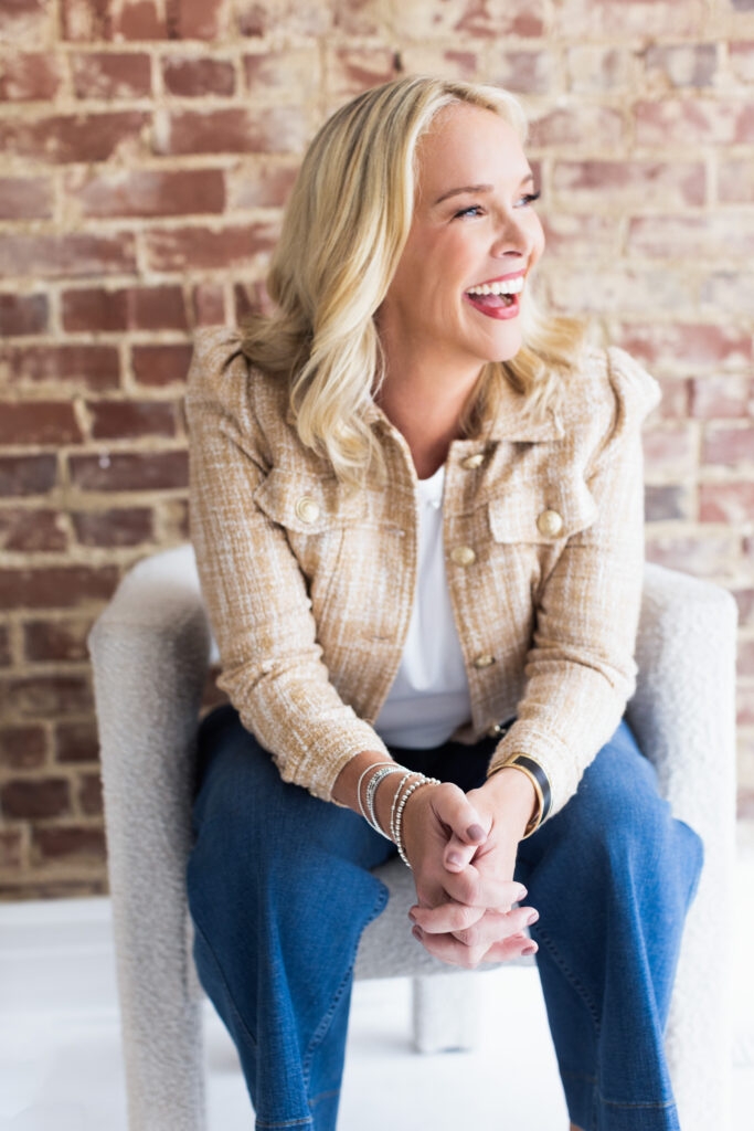 Cathy Major’s approachable and vibrant personality shines in this relaxed personal branding portrait. Seated against a rustic brick wall, she wears a stylish tweed jacket and casual jeans, accessorized with elegant bracelets. Captured at Janel Lee Photography in Cincinnati, this image highlights her warmth and relatability—essential for building trust with high-end travel clients.