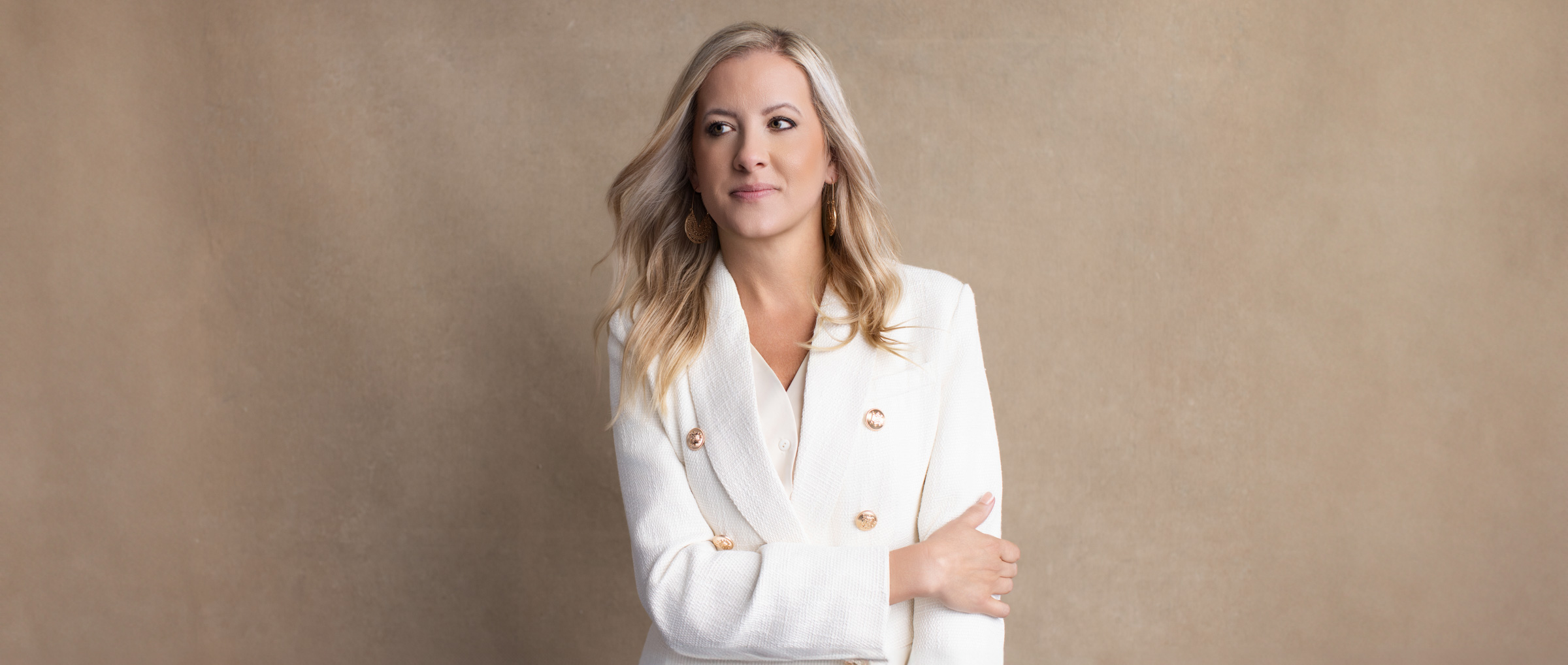 Katie Stuart standing confidently in white suit against neutral backdrop