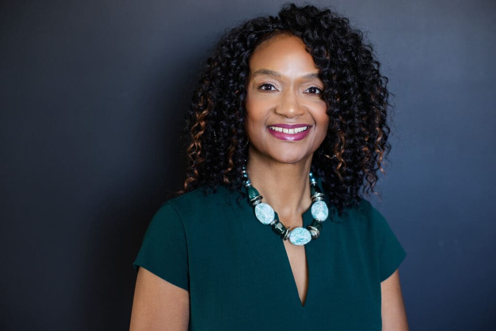 Sheila Eason professional headshot in green dress with dark background
