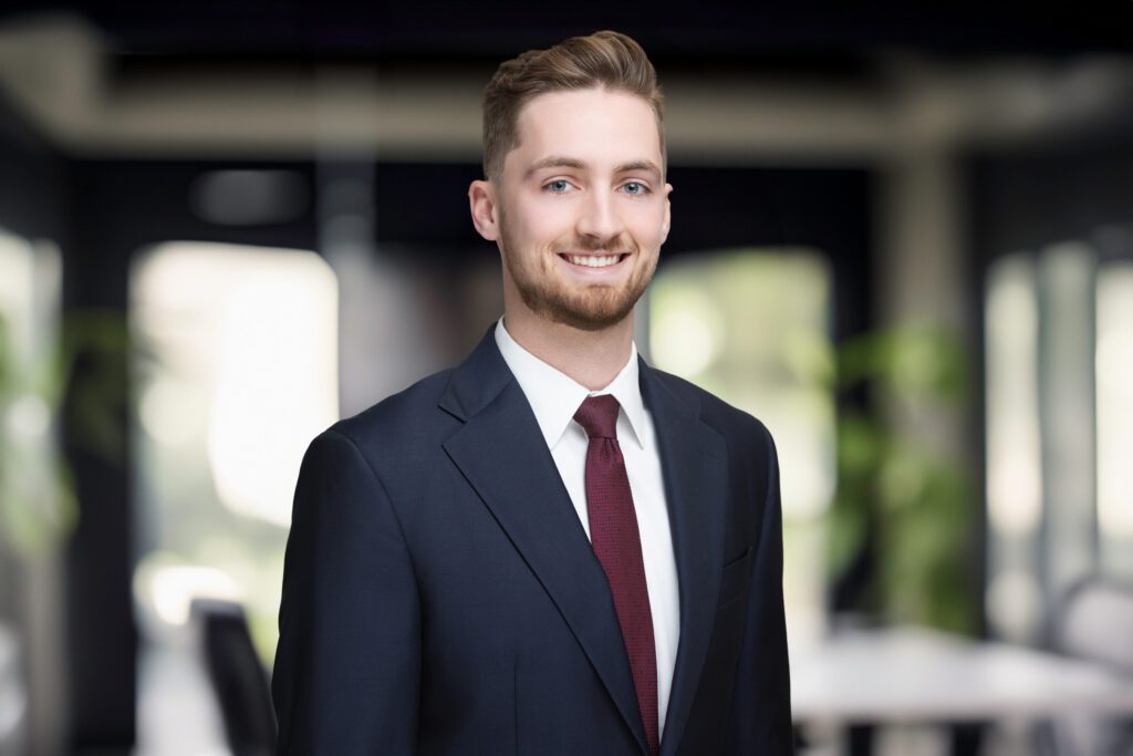 Professional headshot of an Ardlussa Capital team member in Cincinnati Ohio wearing a navy suit and tie in a modern office setting.