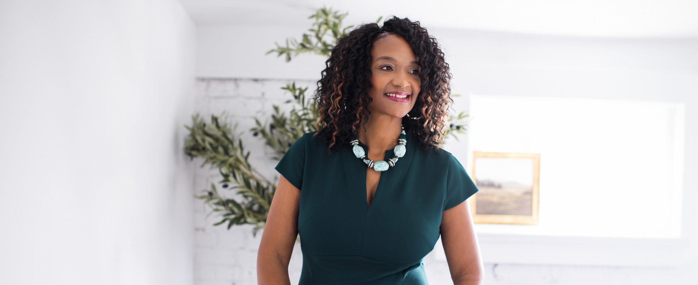 Professional branding portrait of female business professional in Cincinnati Ohio wearing a green dress in a bright modern interior