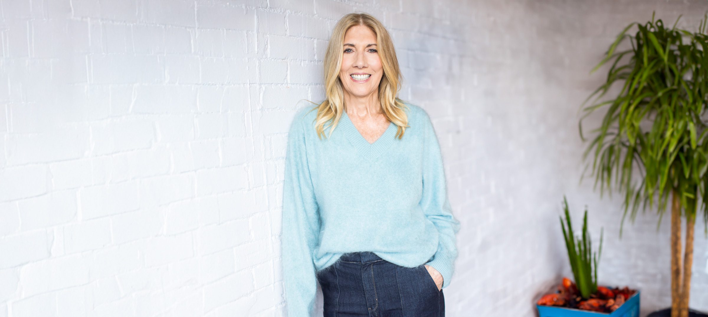 Personal branding portrait of executive coach Shelly Wight in Cincinnati Ohio wearing a light blue sweater against a white brick wall