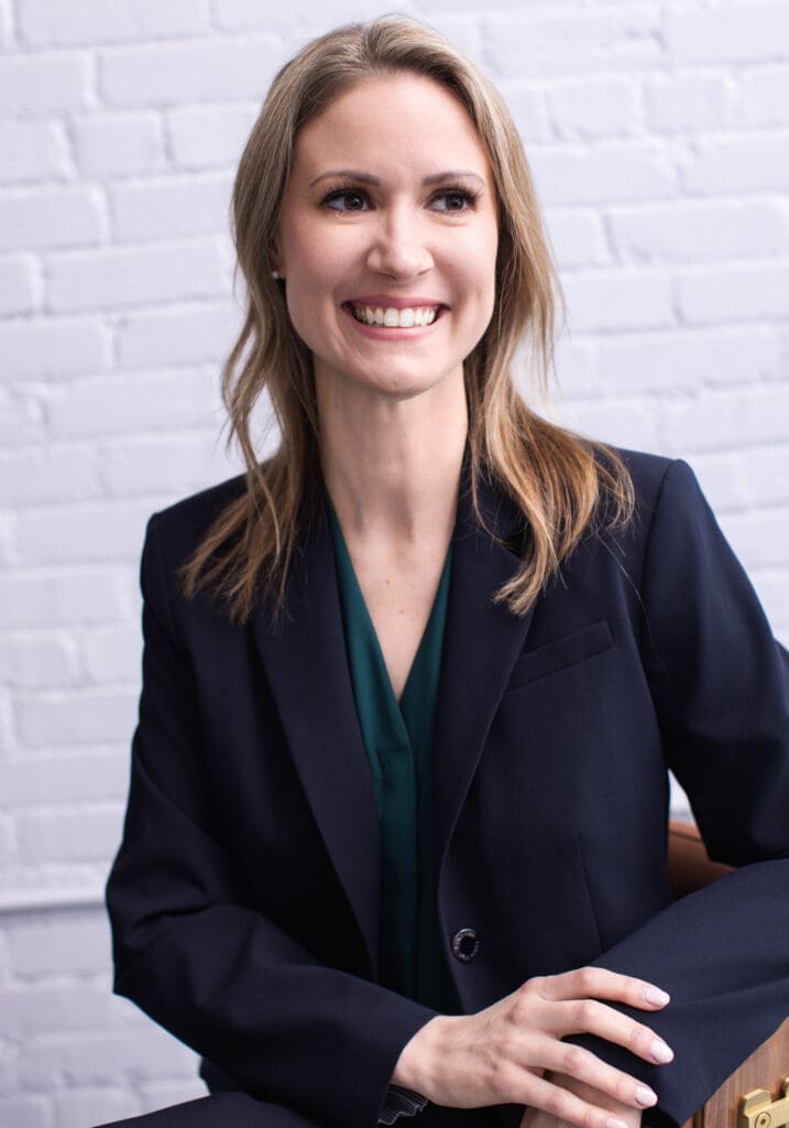 Professional headshot of Lynsey Gaca in Cincinnati, Ohio wearing a navy blazer and green blouse while smiling in a modern personal branding portrait setting.
